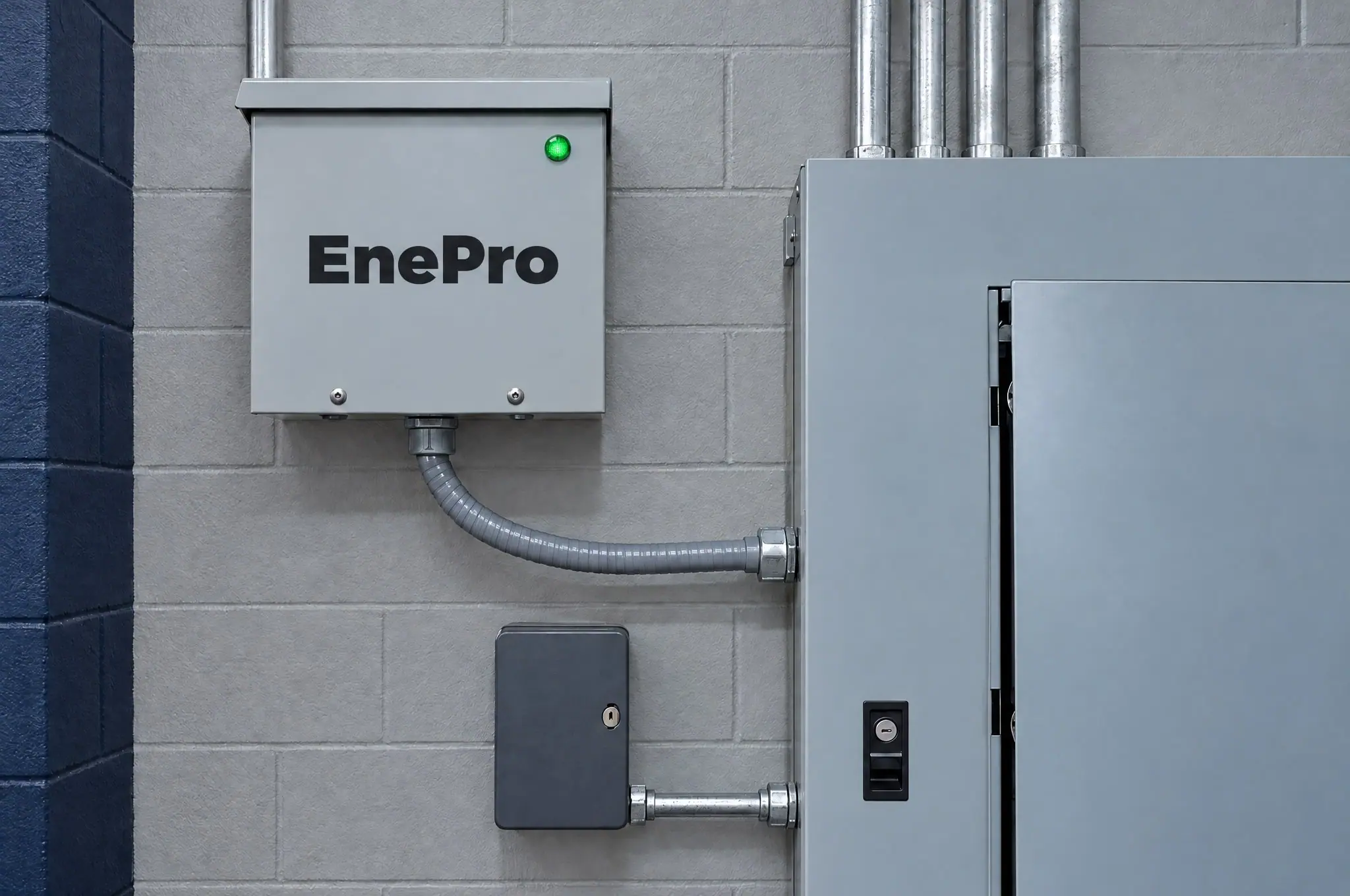 EnePro unit mounted on a block wall beside a commercial electrical service panel
